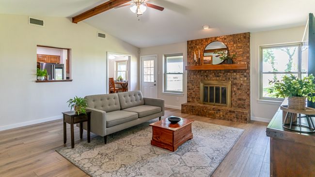 Living area with visible vents, light wood-style flooring, a ceiling fan, and lofted ceiling with beams | Image 17