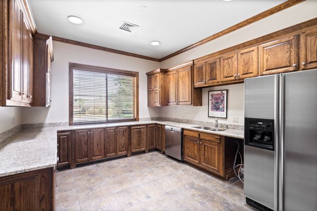 Downstairs Kitchen with stainless steel appliances, crown molding, recessed lighting, light stone counters, and brown cabinetry | Image 14