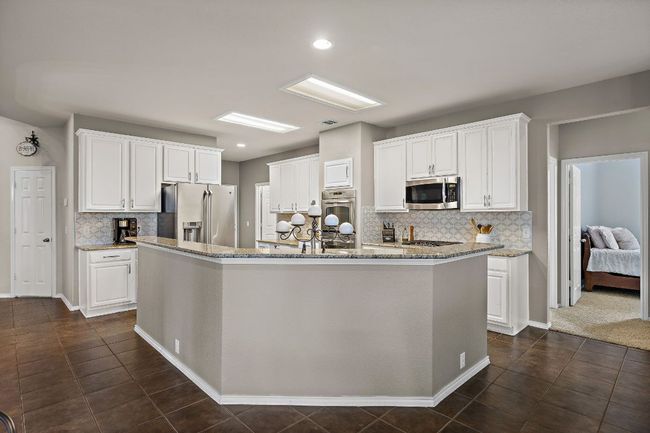 Kitchen featuring appliances with stainless steel finishes, decorative backsplash, white cabinetry, and recessed lighting | Image 11