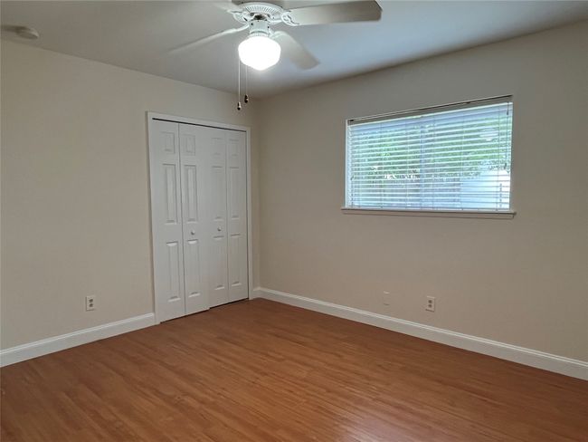 Unfurnished bedroom with wood finished floors, baseboards, a closet, and a ceiling fan | Image 24
