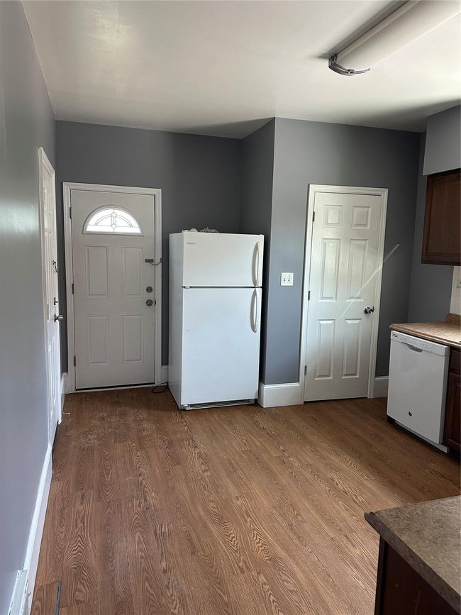 Kitchen with white appliances, a sink, backsplash, light wood-style flooring, and dark countertops | Image 6