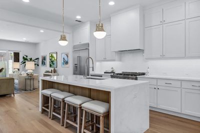 Kitchen with light hardwood / wood-style flooring, an island with sink, sink, white cabinets, and appliances with stainless steel finishes | Image 3