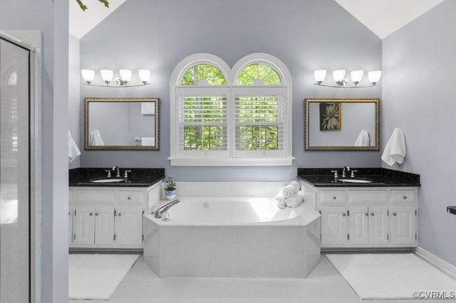 Full bath featuring lofted ceiling, tile patterned floors, two vanities, a bath, and a stall shower | Image 27