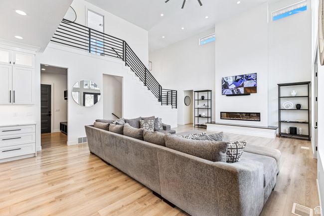 Living area with a towering ceiling, light wood-type flooring, and visible vents | Image 16