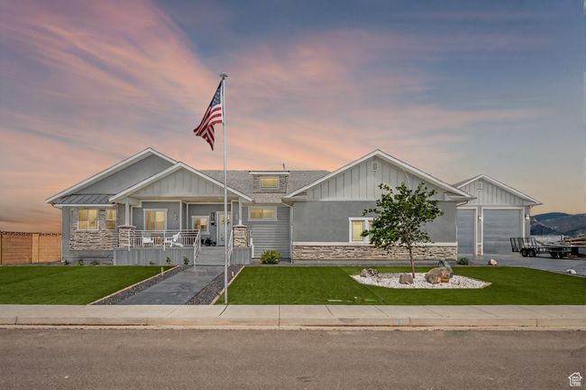View of front of home featuring board and batten siding, a front yard, a porch, and stone siding | Image 4