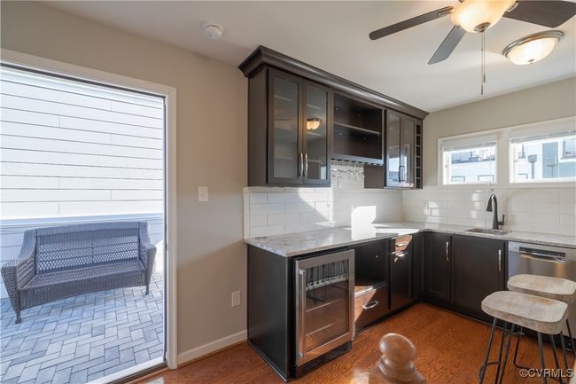 Kitchen with tasteful backsplash, dark hardwood / wood-style flooring, wine cooler, and light stone counters | Image 15