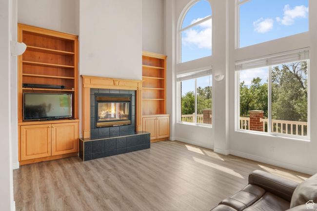 Unfurnished living room with a towering ceiling, plenty of natural light, light wood finished floors, and baseboards | Image 4
