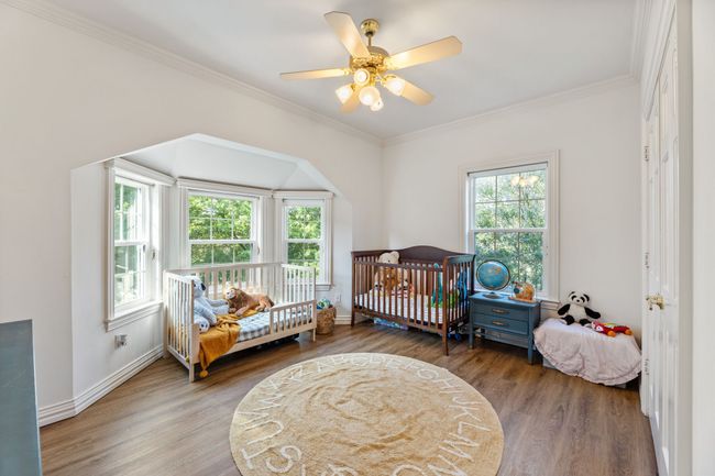 Bedroom with luxury vinyl planking floors, crown molding, and a ceiling fan | Image 28