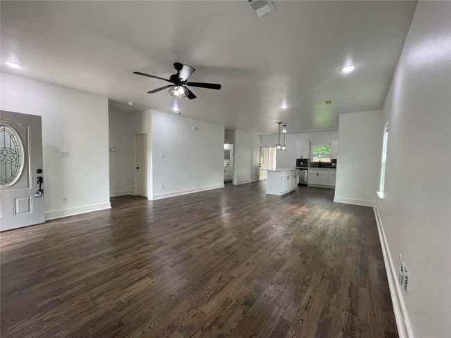 Unfurnished living room with ceiling fan, dark wood-style flooring, baseboards, and recessed lighting | Image 10