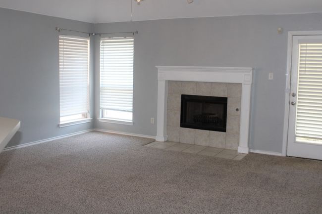 Unfurnished living room featuring carpet floors, baseboards, a ceiling fan, and a tile fireplace | Image 13
