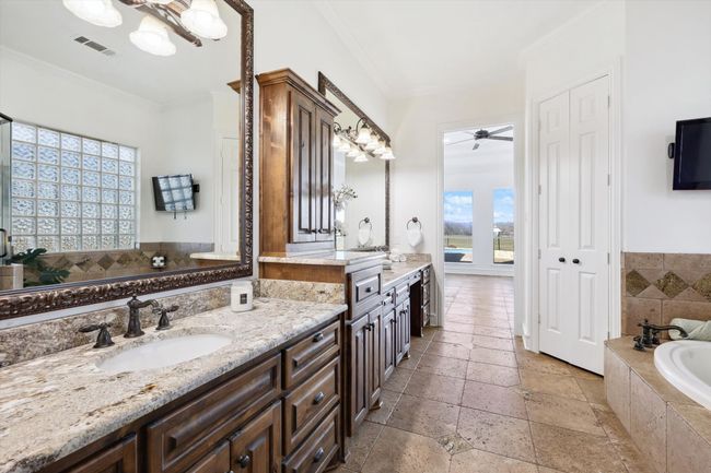 Full bath featuring stone tile flooring, a bath, crown molding, a ceiling fan, and vanity | Image 15