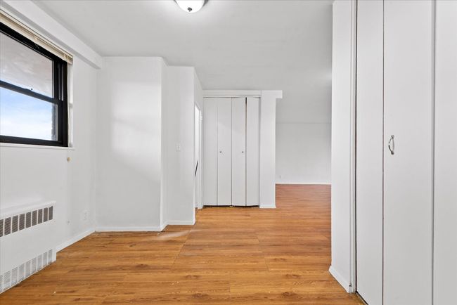 Hallway featuring radiator, light wood-style flooring, and baseboards | Image 9