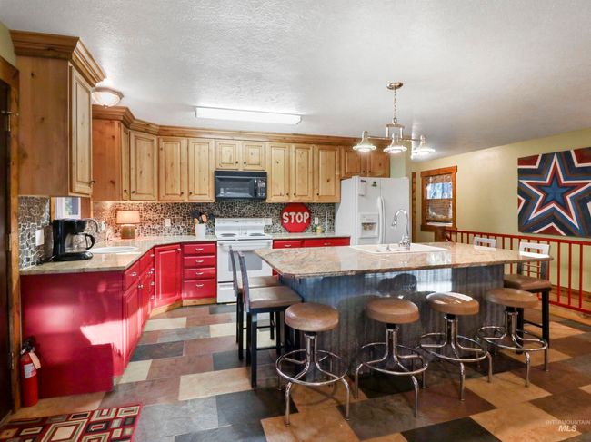 Kitchen with white appliances, a kitchen island with sink, decorative backsplash, a kitchen breakfast bar, and a textured ceiling | Image 26