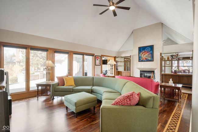 living room with a glass covered fireplace, a healthy amount of sunlight, and dark wood-style flooring | Image 11