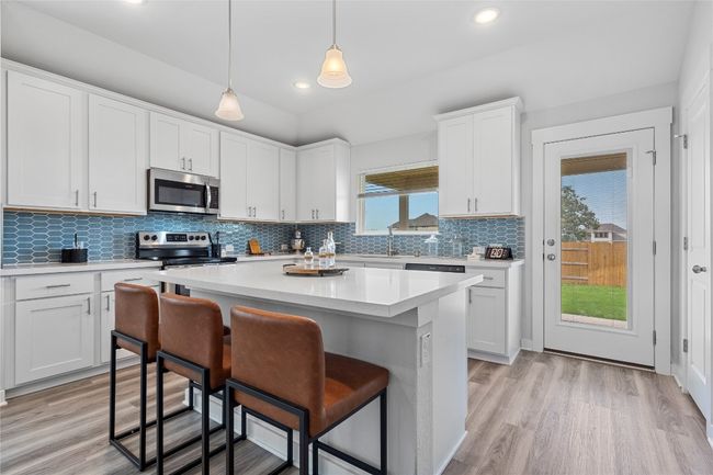 Kitchen featuring appliances with stainless steel finishes, a breakfast bar area, light countertops, recessed lighting, and a sink | Image 11