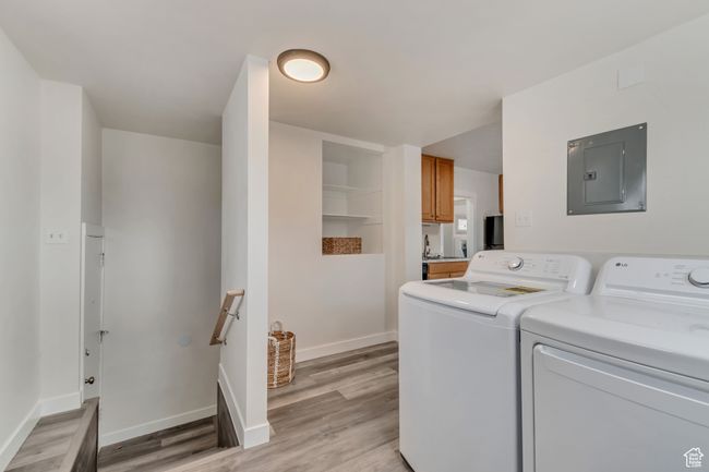 Clothes washing area with electric panel, independent washer and dryer, light wood finished floors, and baseboards | Image 13