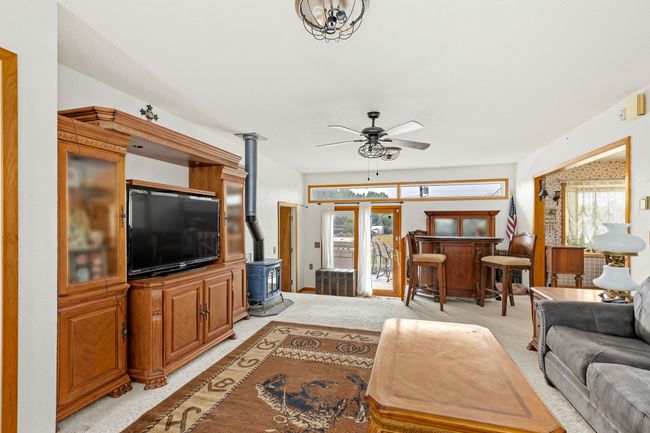Living area featuring light carpet, ceiling fan, and a wood stove | Image 36