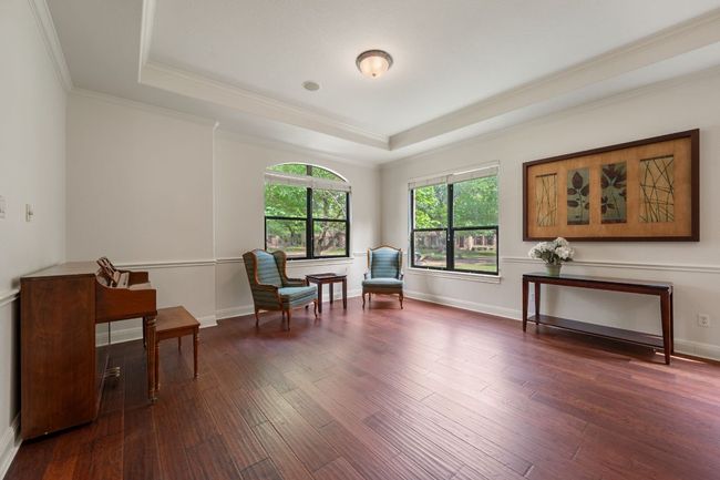Living area with dark wood-type flooring, crown molding, a tray ceiling, and baseboards | Image 17