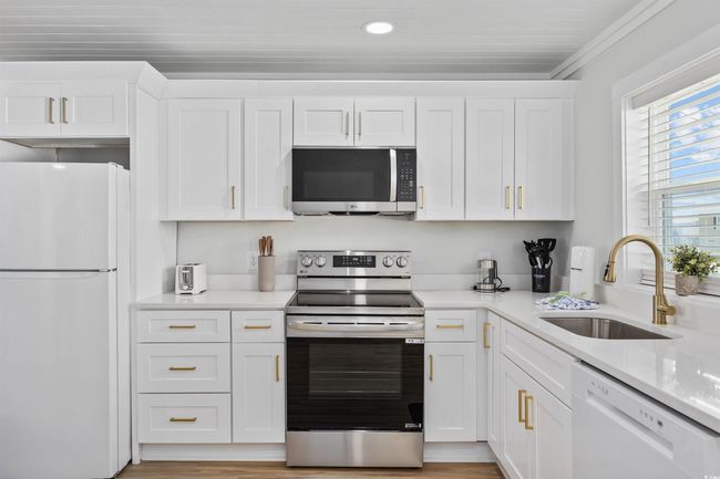Kitchen featuring appliances with stainless steel finishes, a sink, white cabinetry, light countertops, and recessed lighting | Image 8