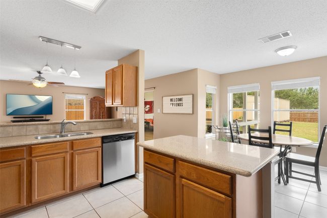 A delightful kitchen awaits, featuring a double sink and a convenient dishwasher. The open layout seamlessly connects to the secondary dining nook, enhancing the spacious feel, complemented by hanging light fixtures. It's the perfect hub for culinary creativity! | Image 22