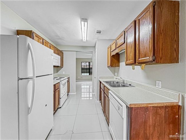 Kitchen featuring sink, white appliances, and light tile patterned flooring | Image 9