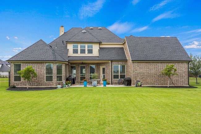 Rear view of property with a chimney, a shingled roof, brick siding, and a patio area | Image 22
