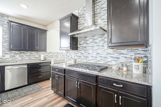 kitchen featuring stainless steel appliances, wall chimney exhaust hood, and tasteful backsplash | Image 20