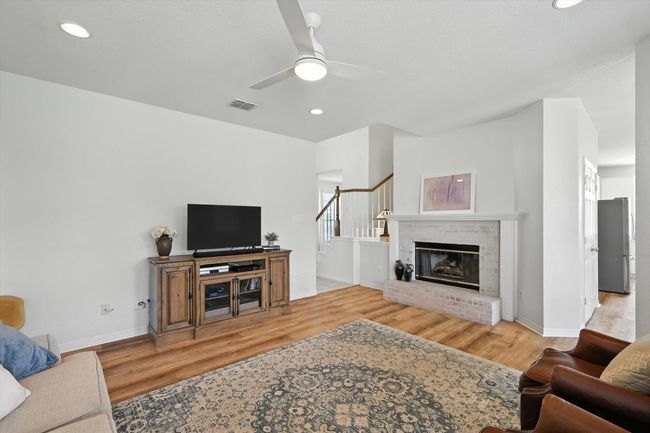 Living room with wood finished floors, a ceiling fan, recessed lighting, and a fireplace | Image 12