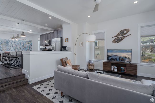 Living area with dark wood-style flooring, baseboards, beamed ceiling, recessed lighting, and ceiling fan | Image 7