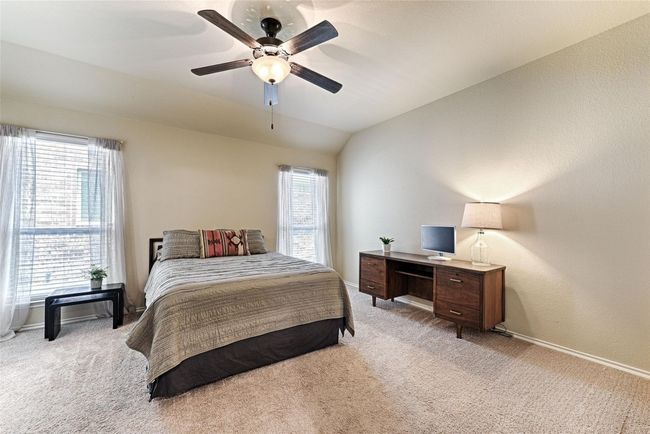 Bedroom featuring light colored carpet, vaulted ceiling, ceiling fan, and a desk | Image 12