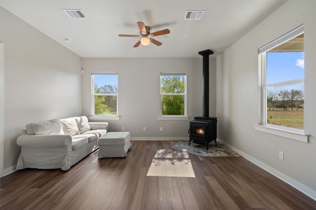 Living room featuring a wood stove, ceiling fan, dark wood-style floors, and baseboards | Image 30