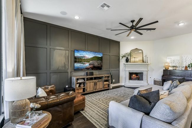 Living room with a decorative wall, visible vents, a ceiling fan, and dark wood-style floors | Image 7