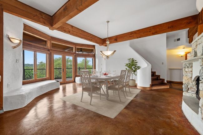 Dining area featuring finished concrete flooring, healthy amount of natural light, stairway, and beamed ceiling | Image 5