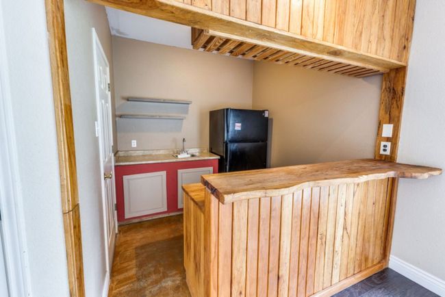 Kitchen with open shelves, a sink, freestanding refrigerator, baseboards, and wood counters | Image 15