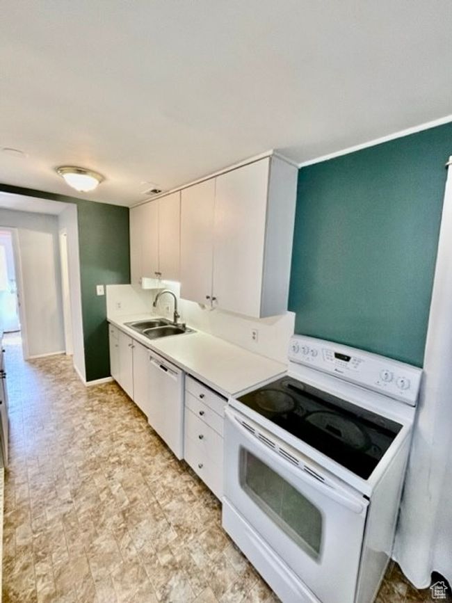 Kitchen with a sink, light countertops, white cabinets, and white appliances | Image 11
