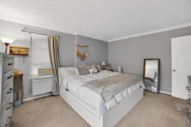 Carpeted bedroom with ornamental molding, a textured ceiling, and cooling unit | Image 16