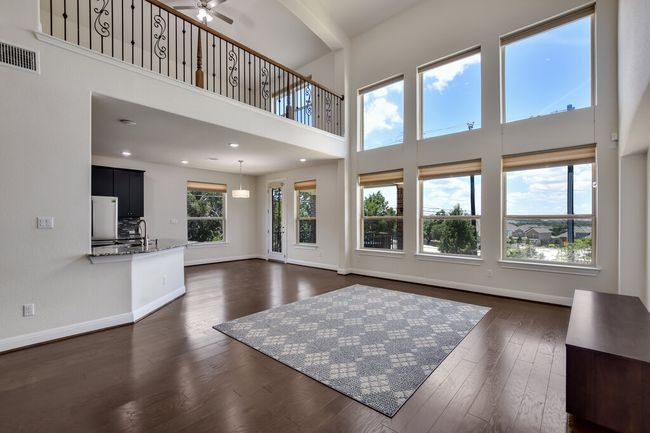 Living room featuring a towering ceiling, dark wood finished floors, and a ceiling fan | Image 18