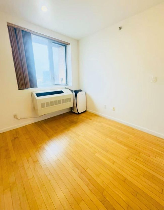 Unfurnished room with light wood-style floors, a wall unit AC, and baseboards | Image 4