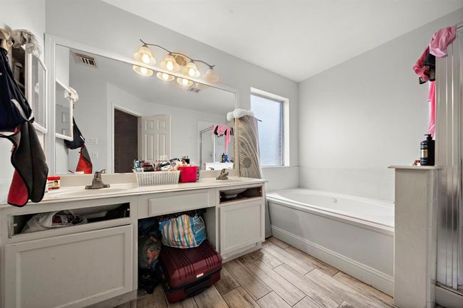 The ensuite bathroom features a smart layout with separate vanities, allowing for personal space and added functionality. The oversized mirror, built-in lighting, and ample under-sink storage make the space feel both luxurious and efficient. | Image 19