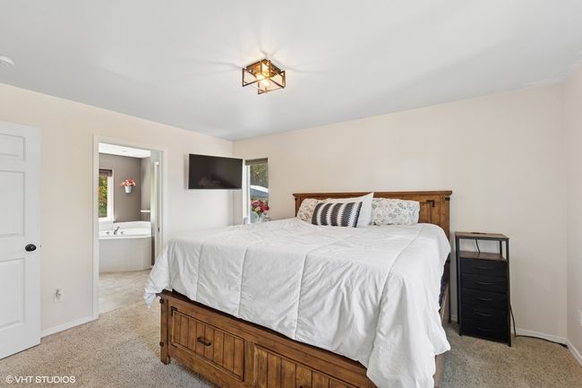 Bedroom with light colored carpet, baseboards, and ensuite bath | Image 18