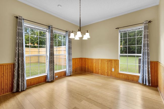 Spare room featuring wainscoting, a chandelier, plenty of natural light, wood finished floors, and wooden walls | Image 9