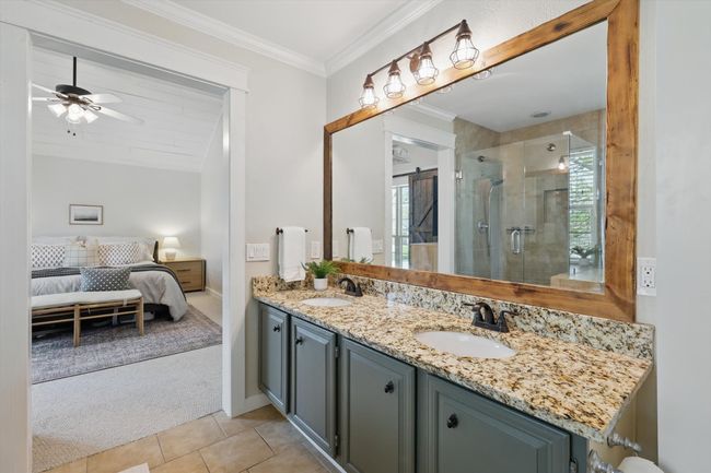 Bathroom with ensuite bathroom, double vanity, a stall shower, a ceiling fan, and tile patterned floors | Image 19