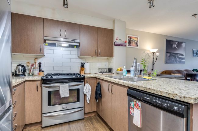 Kitchen with a sink, appliances with stainless steel finishes, a peninsula, under cabinet range hood, and decorative backsplash | Image 5