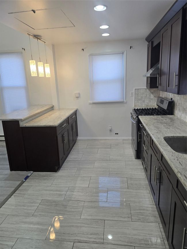 Kitchen featuring backsplash, a sink, light stone countertops, range, and exhaust hood | Image 10