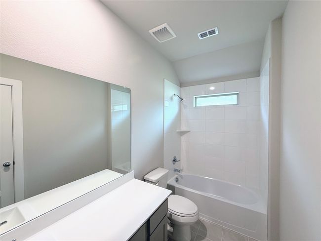 Bathroom with toilet, vanity, shower / bath combination, tile patterned flooring, and lofted ceiling | Image 19