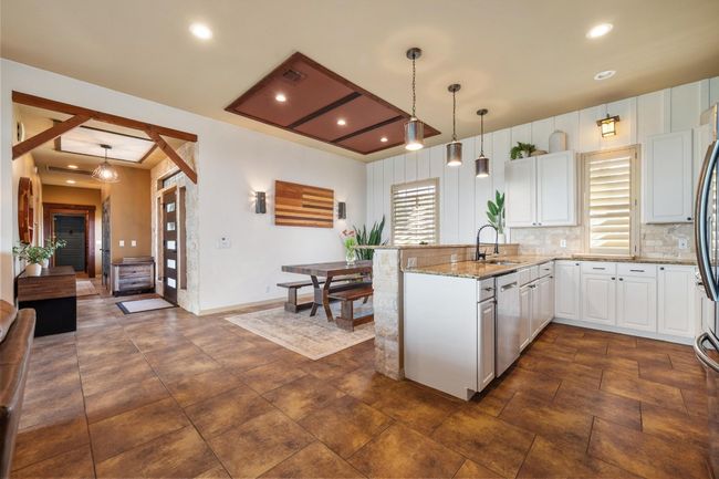 Kitchen featuring light stone counters, a sink, tasteful backsplash, a peninsula, and white cabinets | Image 10