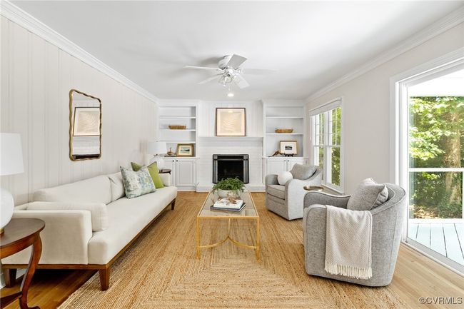 Family room with crown molding, hardwood flooring, a ceiling fan, wood-burning fireplace, built in cabinets. Also has patio doors to screened in porch. | Image 20