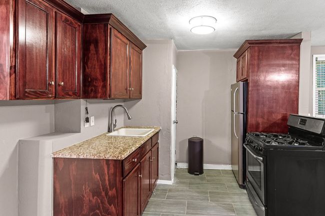 Kitchen with appliances with stainless steel finishes, a sink, light countertops, baseboards, and dark brown cabinets | Image 34
