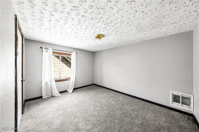 Carpeted spare room with a textured ceiling, visible vents, and baseboards | Image 14