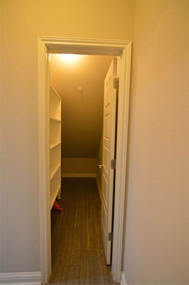 Spacious closet under stairs with built in shelves, featuring vaulted ceiling | Image 9